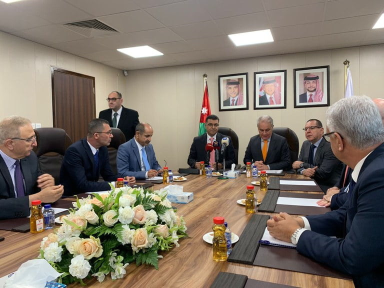 Foto de homens sentados ao redor de mesa durante reunião.