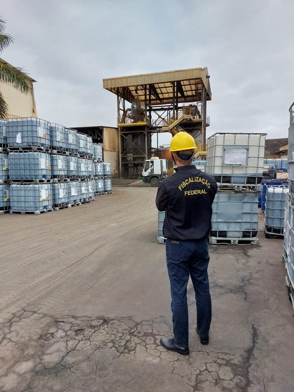 Foto de fiscal federal de costas observando operações em fábrica.