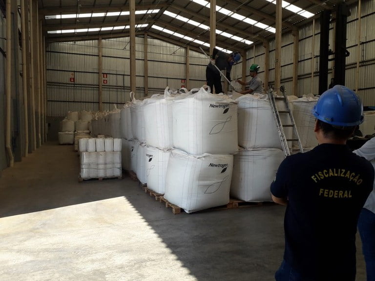 Foto de auditor fiscal federal agropecuário de costas enquanto olha para galpão com insumos.