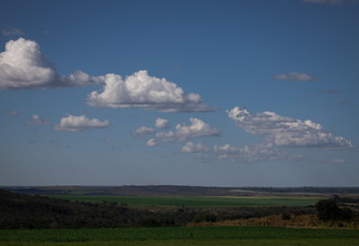 Foto de campos e céu com poucas nuvens.