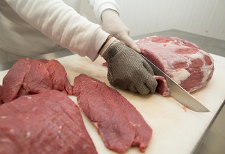 Foto de carne bovina sendo cortada em indústria.