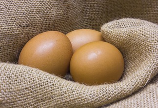 A foto mostra três ovos sobre um tecido de juta