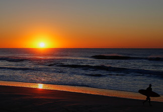 A foto mostra uma praia e o nascer do sol