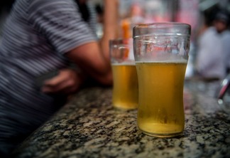 Foto de dois copos de cerveja sobre bancada.