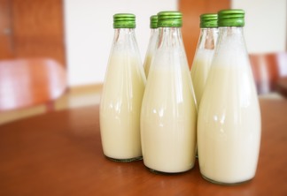 A foto mostra garrafas de vidro com leite