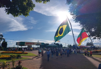 Foto de pessoas e bandeiras em frente ao pórtico da Expodireto Cotrijal.
