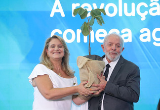 Foto do presidente Lula e da presidente da Embrapa, Silvia Massruhá, segurando uma muda de pequi sem espinhos enquanto posam para foto.
