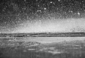 Foto de chuva caindo em poças de água.