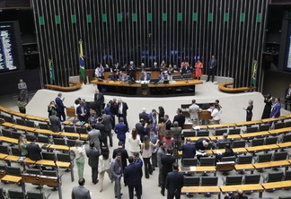 Foto do plenário do Congresso Nacional com políticos sentados à mesa da presidência e os demais em pé na frente do plenário.