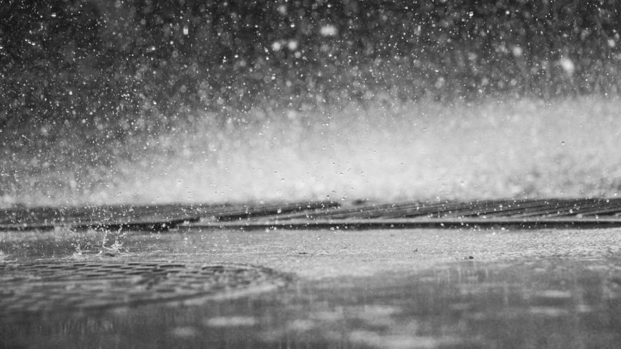 Foto de chuva caindo em poças de água.
