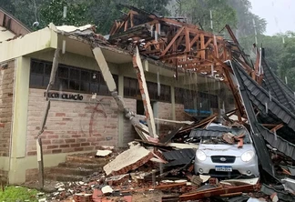 Foto de prédio com parte da cobertura destruída e caída sobre carro.