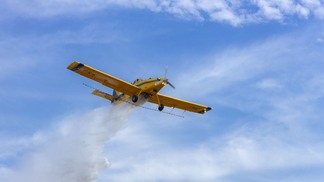 Foto de aviação agrícola sobrevoando e realizando a pulverização.