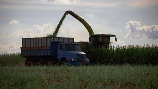 Foto de colheitadeira despejando grãos em caminhão.
