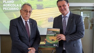 Foto do presidente da CNA, João Martins, ao lado do ministro da Agricultura, Carlos Fávaro. O ministro segura o Plano Agrícola e Pecuário (PAP) 2024/2025 enquanto posa para a foto.