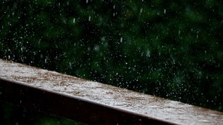 Foto de gotas de chuva caindo sobre madeira.