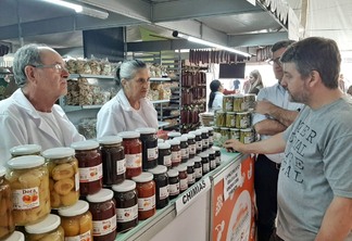 Foto de pessoas em frente a expositor com chimias. Foto de pessoas em frente a expositor com chimias.