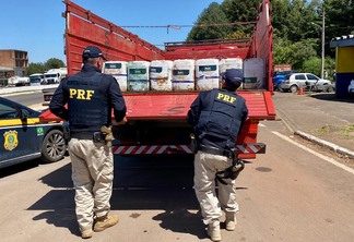 Foto de policiais rodoviários federais próximos a caminhão com galões de agrotóxicos.