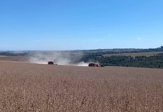 Imagem mostra duas colheitadeiras e um transportador de grãos em uma lavoura de soja