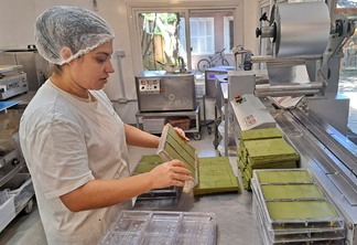 Foto de mulher com EPI em fábrica realizando a produção de chocolate branco com erva-mate.
