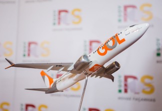 Foto de miniatura de avião da empresa GOL em frente a painel com logos do governo do RS. Foto de miniatura de avião da empresa GOL em frente a painel com logos do governo do RS.