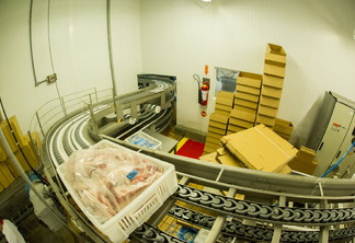 Foto de embalagens de carne em esteira industrial.
