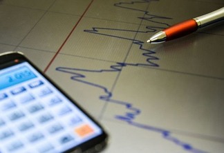 Foto de calculadora sobre papel com gráfico. Foto de calculadora sobre papel com gráfico.