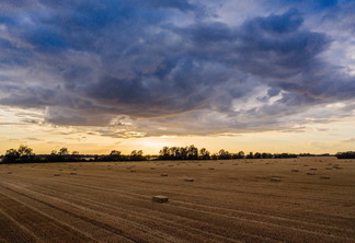 A imagem mostra um terreno rural, e um céu com nuvens de chuva