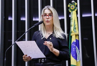 A foto mostra a deputada Soraya Manato, mulher de cabelos platinados, usando camisa azul e óculos com armação vermelha. A foto mostra a deputada Soraya Manato, mulher de cabelos platinados, usando camisa azul e óculos com armação vermelha.