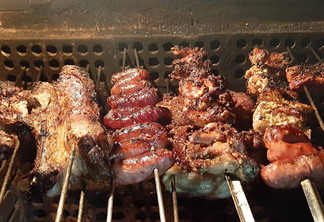 A foto mostra carnes de gado e de frango e linguicinhas no espeto