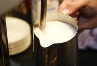 A foto mostra uma caneca com leite A foto mostra uma caneca com leite