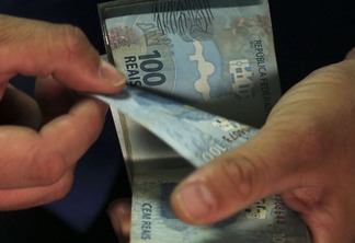 Foto de mãos contando notas de cem reais. Foto de mãos contando notas de cem reais.