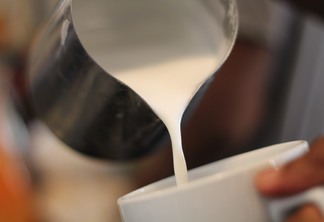 A imagem mostra um recipiente de inox com lente sendo despejado sobre uma xícara de porcelana