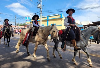 A foto mostra algumas pessoas andando à cavalo