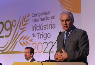 Foto de Marcos Montes discursando em púlpito em frente a banner do Congresso Internacional da Indústria do Trigo 2022.