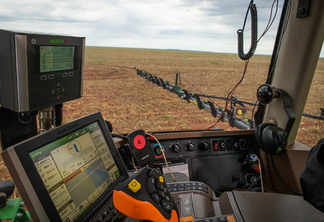Foto de interior de máquina agrícola com diversas tecnologias e monitores.