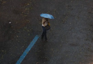 Foto de pessoa com guarda-chuva andando em meio a chuva. Foto de pessoa com guarda-chuva andando em meio a chuva.