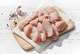 Foto de tábua com pedaços de carne de frango e tempero.
