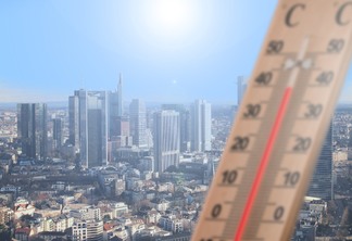 A foto mostra um termômetro e uma cidade
