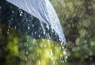 A foto mostra um guarda-chuva e a chuva caindo sobre o objeto