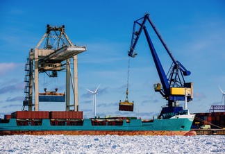 A foto mostra um porto industrial com contentores, carregamento de embarcações no porto da Finlândia