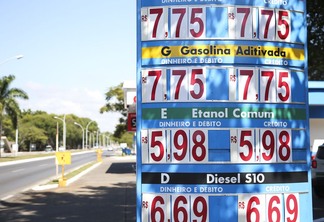 A foto mostra uma placa de preços localizada em um posto de combustível