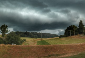 A foto mostra nuvens de chuva e terrenos cultiváveis de lavoura