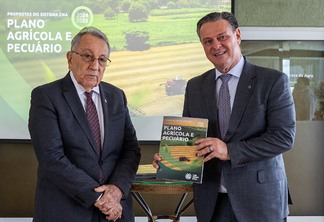 Foto do presidente da CNA, João Martins, ao lado do ministro da Agricultura, Carlos Fávaro. O ministro segura o Plano Agrícola e Pecuário (PAP) 2024/2025 enquanto posa para a foto.