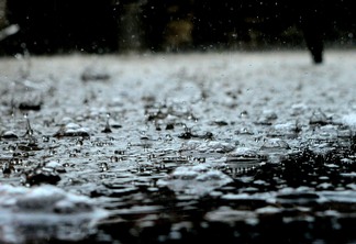 Foto de poça de água com chuva caindo.