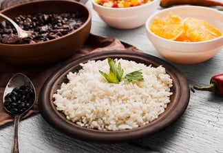 Foto de prato de arroz, ao lado de prato com laranja e com um prato de feijão ao fundo.