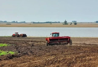 Foto de máquinas vermelhas realizando a semeadura do arroz perto de rio ou lago. Foto de máquinas vermelhas realizando a semeadura do arroz perto de rio ou lago.