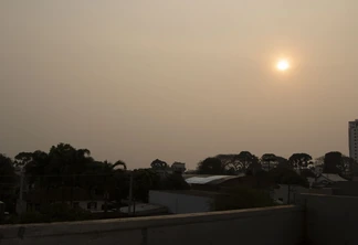 Foto de céu acizentado com sol avermelhado sobre cidade. Foto de céu acizentado com sol avermelhado sobre cidade.