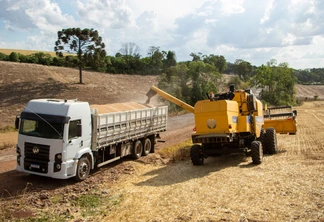 Foto de colheitadeira amarela despejando grãos de trigo em carreta. Foto de colheitadeira amarela despejando grãos de trigo em carreta.