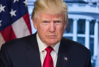 Foto de Donald Trump. Ele está sério, usa terno preto e gravata vermelha e está em frente a bandeira dos EUA e de foto da Casa Branca. Foto de Donald Trump. Ele está sério, usa terno preto e gravata vermelha e está em frente a bandeira dos EUA e de foto da Casa Branca.