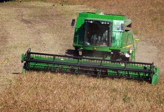 Foto de colheitadeira verde avançando em lavoura de feijão. Foto de colheitadeira verde avançando em lavoura de feijão.